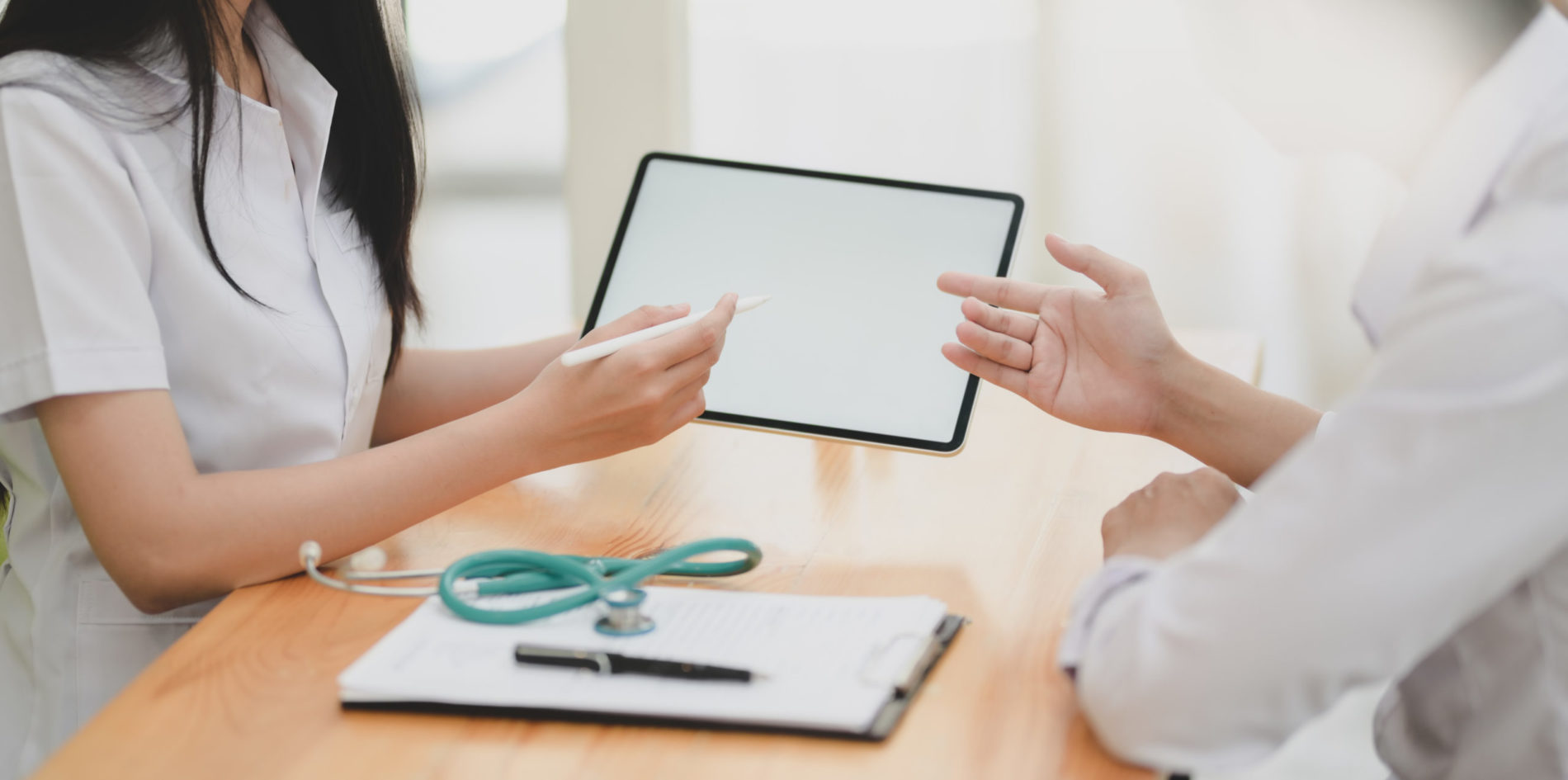 2 healthcare workers looking at a chart with a stethoscope on the table